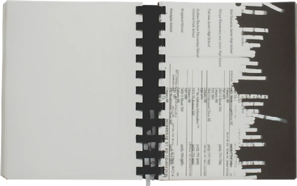 Open book. One side of the spread shows what looks like an old invoice. The edge of the page gives the illusion that the page has gone through a paper shredder.